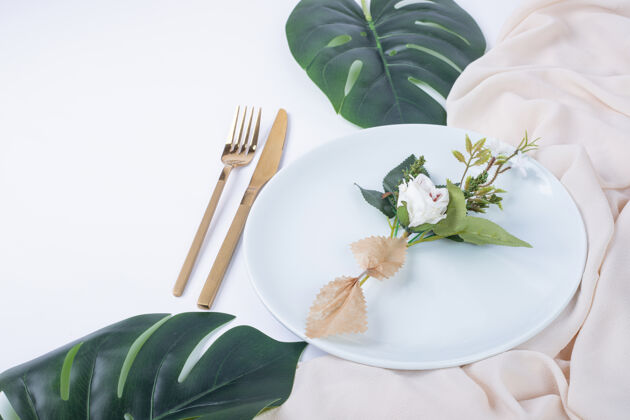 绿一朵玫瑰放在白色的盘子里 上面有假叶子和桌布常绿桌布人造的