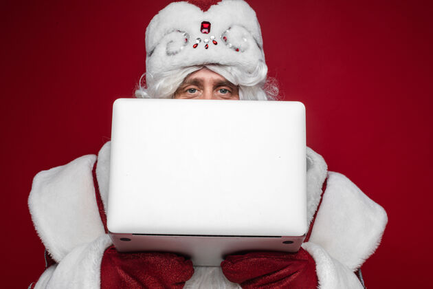 电脑圣诞老人躲在笔记本电脑后面圣诞老人圣诞老人庆祝