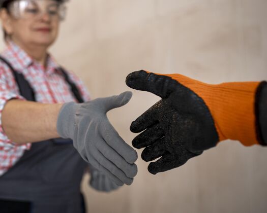技能戴着头盔和手套的女建筑工人握手工作老年人职业