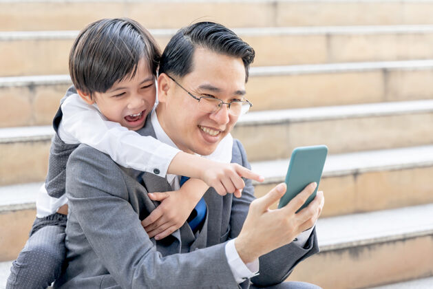 儿子父子俩在市区商业区一起玩智能手机商业通信孩子