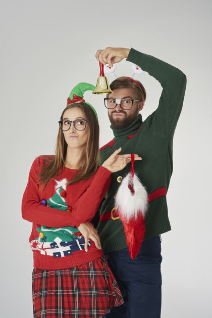 结合一对情侣摆着圣诞钟和圣诞袜庆祝眼镜女人