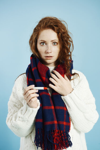 数码体温计震惊的女人拿着数字温度计在摄影棚里检查温度冬天保暖衣服感冒