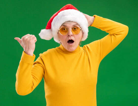 侧一位戴着太阳眼镜 戴着圣诞老人帽子的老妇人惊讶地站在一旁复制老人指向