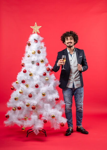 礼物圣诞节庆祝活动与留胡子的年轻人与葡萄酒站在圣诞树附近的红色男人站着葡萄酒