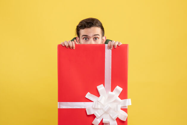 写作工具正面图：年轻人躲在黄色的大礼品盒后面礼品盒礼物人