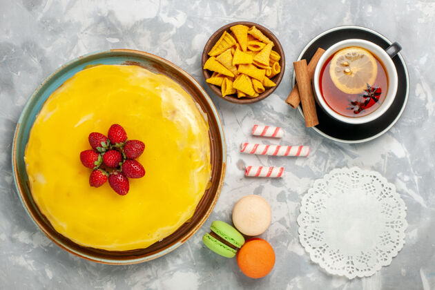 食物顶视图黄色蛋糕 白色背景上有草莓蛋糕和一杯茶餐背景蛋糕