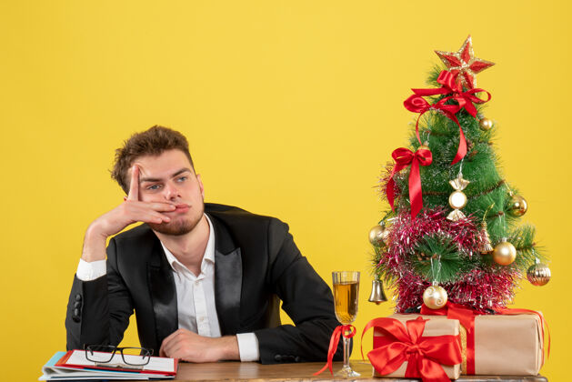 圣诞节正面图：坐在黄色工作台后面的男工人工作工人情感
