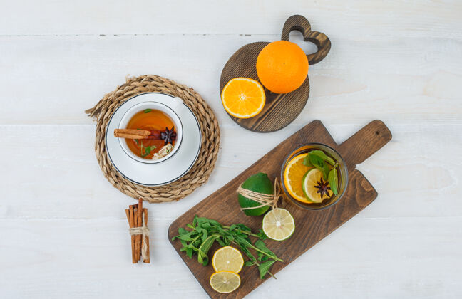 有机一杯带有柑橘类水果 切菜板上的薄荷叶和白色表面上的肉桂的凉茶茶柑橘干燥