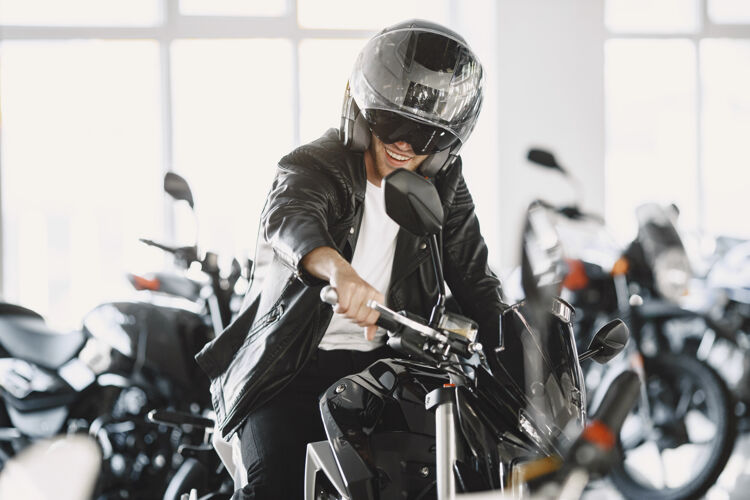 商店一个男人在摩托店里选摩托车一个穿黑夹克的男人一个戴头盔的男人摩托车头盔商店
