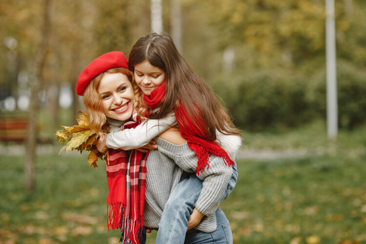 蓝色时髦的母亲带着女儿黄色的秋天戴着红领巾的女人父母时尚成人