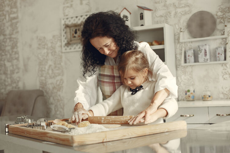 家厨房里的人奶奶带着小女儿成年妇女教小女孩做饭孩子烹饪成人