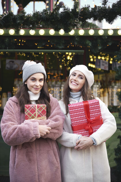庆祝圣诞集市上两个拿着礼物的女人的画像零售城市市场