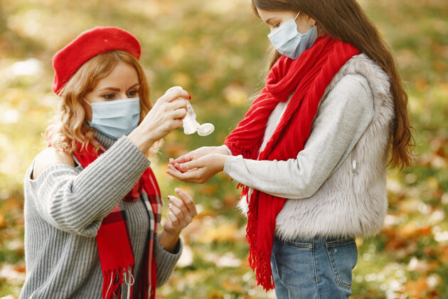 面具秋天公园里的一家人冠状病毒主题母亲带女儿人们用杀菌剂孩子问题家庭