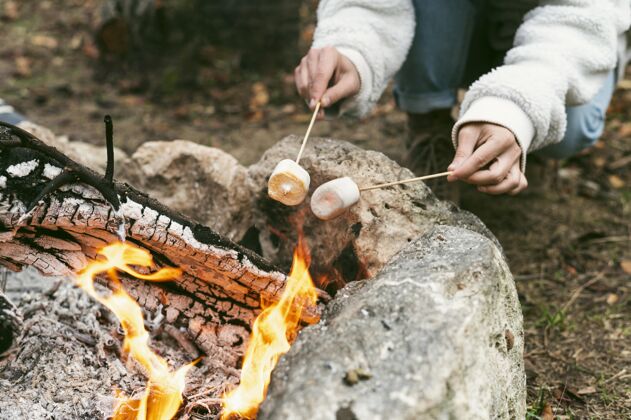 冬天冬天在营火里烧棉花糖的年轻女人火户外露营