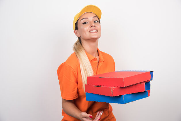 微笑一个戴着黄色帽子的女送货员拿着比萨饼盒在空白处食物手势保持