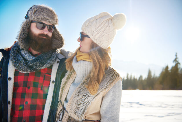 户外穿着暖和衣服的夫妇在山里开朗阳光欣赏