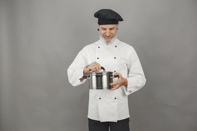 烹饪戴着金属锅的高级男人戴着黑帽子的厨师银厨师灰色