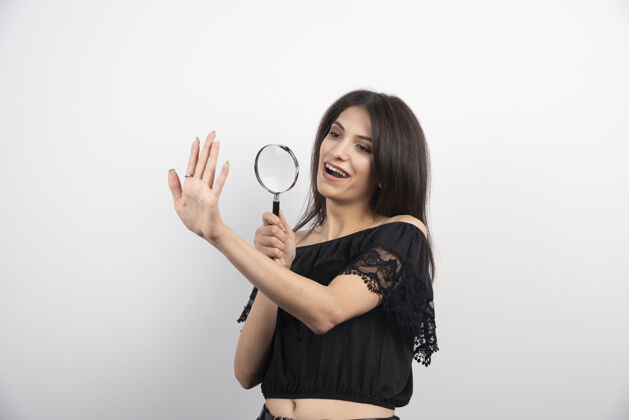 放大镜黑发女人用放大镜看着她的手姿势女人放大镜