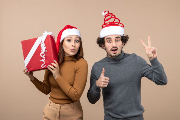 圣诞老人新年气氛喜庆的概念与有趣可爱的夫妇穿着灰色的红色圣诞老人帽子帽子团体男人