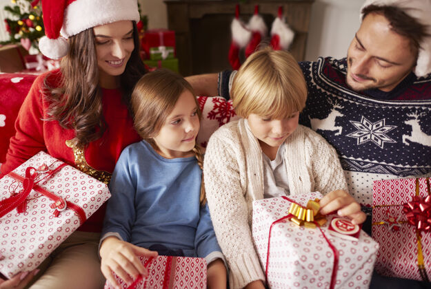 孩子一家人坐在家里拿着圣诞礼物沙发装饰品结合