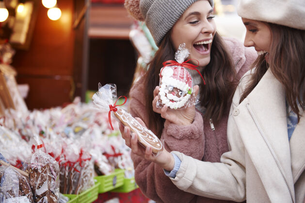 消费主义两个女人在圣诞集市上买姜饼游客装饰品圣诞装饰