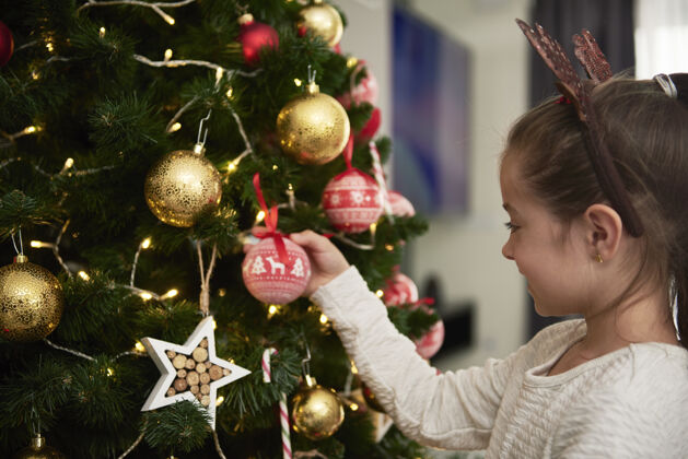 悬挂孩子在装饰圣诞树房间向上球