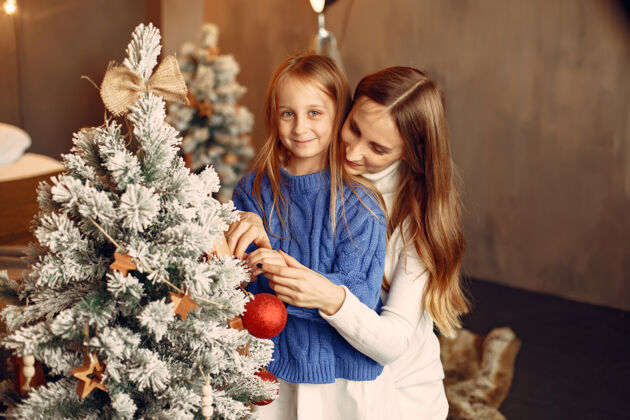 肖像人们在为圣诞节做准备母亲在和女儿玩耍一家人在节日的房间里休息孩子穿着蓝色毛衣孩子童年爱