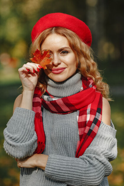 叶子戴着红色贝雷帽的美女手里拿着秋叶肖像女孩看起来