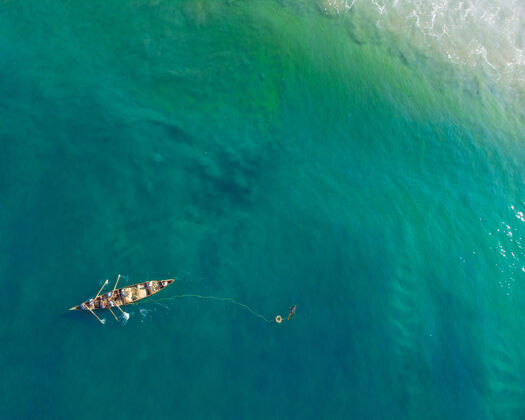 岩石瓦卡拉海滩上人们在船上钓鱼的俯视图海岸人波浪