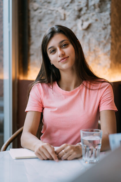 姿势咖啡馆里一位年轻漂亮的黑发女郎的画像女性桌子人