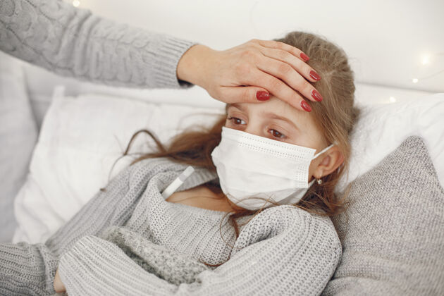 疾病儿童中有冠状病毒母亲带着女儿孩子躺在床上戴着医用口罩的妇女冠状病毒发烧儿童