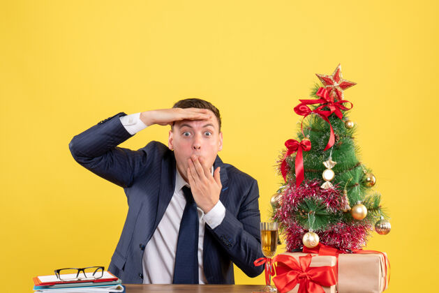 秘书一个好奇的男人坐在圣诞树旁的桌子前看着什么东西 黄色的礼物礼物黄色什么
