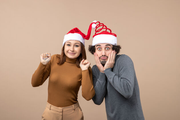 男性节日喜庆和派对理念-快乐可爱惊喜的年轻情侣穿上彼此团结的圣诞老人帽子可爱肖像