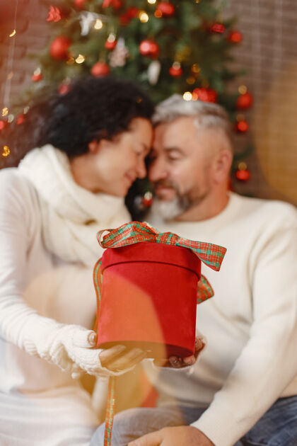 装饰品年龄和人的概念家里的老年夫妇穿着白色针织毛衣的女人庆祝传统圣诞树