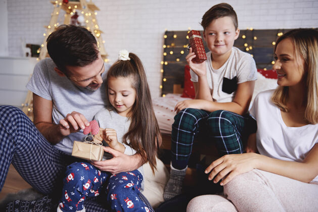 爱快乐的家庭在床上打开圣诞礼物家庭舒适盒子