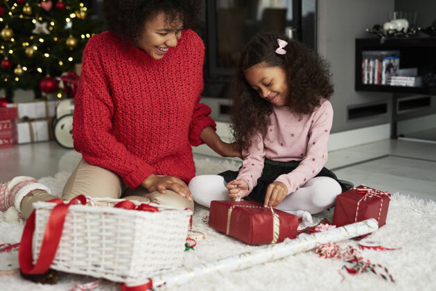 母亲女人和她的女儿在打包圣诞礼物包家庭内部庆祝