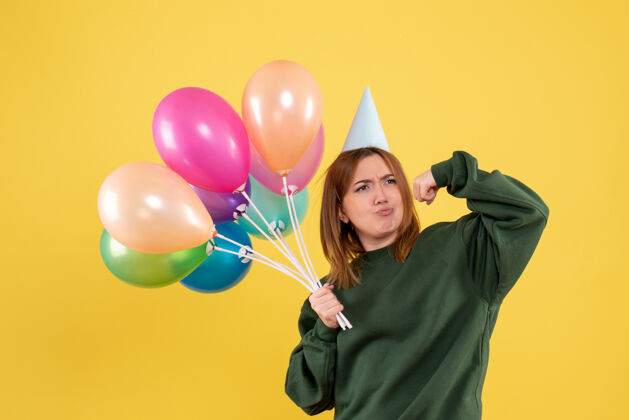 乐趣正面图是一位年轻的女士 手里拿着五颜六色的气球聚会节日飞机