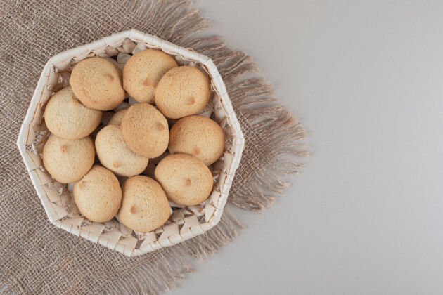 篮子在大理石背景上的一块布上放在一个白色篮子里的易碎饼干美味易碎商品
