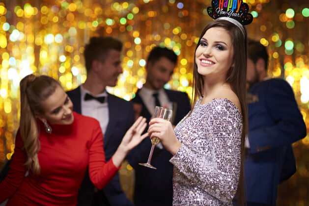 社交聚会戴着派对皇冠的漂亮女人快乐照明人群