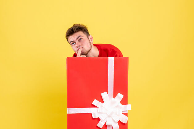 圣诞正面图年轻男子躲在礼品盒里思考颜色购物隐藏
