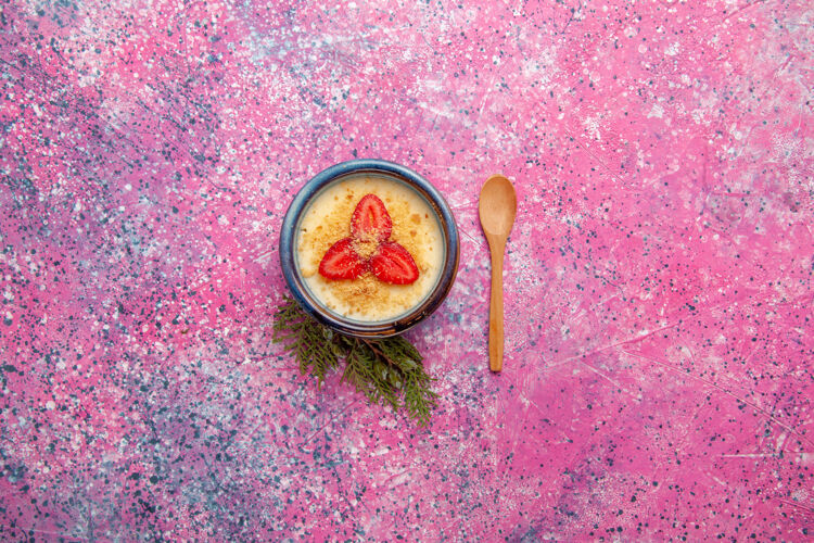 水果顶视图美味的奶油甜点与淡粉色背景上的红色切片草莓甜点冰淇淋甜水果浆果勺子切片的冰淇淋