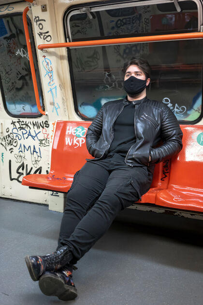 悲伤一个戴着黑色医用面罩的白种人坐在地铁的椅子上 里面涂着油漆医疗火车预防