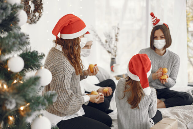 内部为圣诞节做准备的人两个母亲和他们的孩子玩耍冠状病毒隔离孩子帽子童年