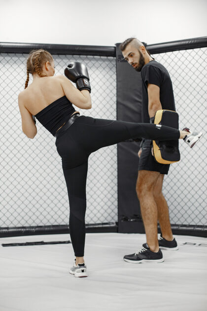 拳击手女子拳击健身房的初学者穿黑色运动服的女士有教练的女士跆拳道活跃武术