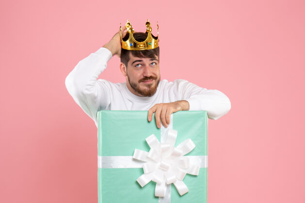 粉色礼物盒内年轻人的正面图 粉色墙上头戴皇冠前面情感圣诞节