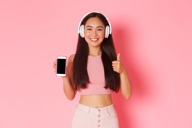 智能手机一个戴着耳机听音乐的富有表情的年轻女子黑发播客耳机
