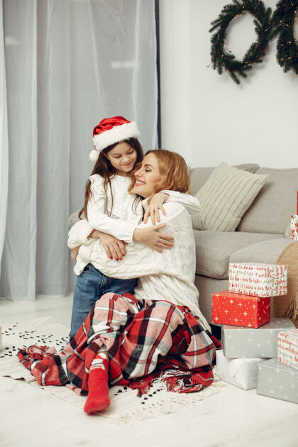 杉木人们在为圣诞节做准备母亲在和女儿玩耍一家人在节日的房间里休息孩子穿着红色毛衣装饰女儿母亲