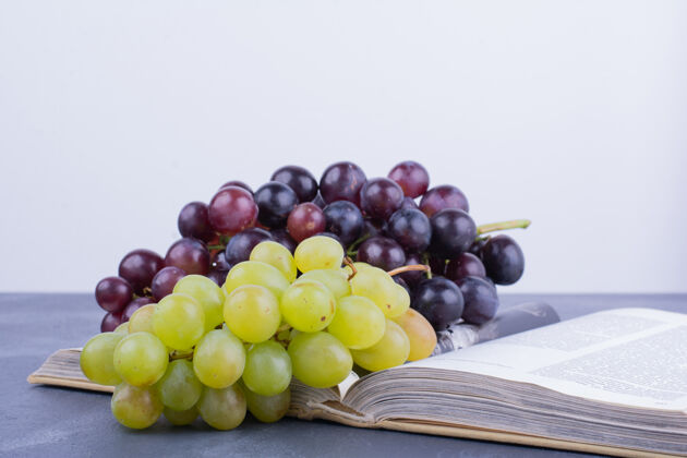 浆果绿色和红色的葡萄串在书上素食成分酸味