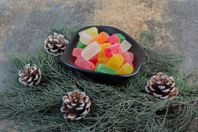 形状一个黑暗的盘子里装满了甜果冻糖果和松果高质量的照片甜点含糖食物