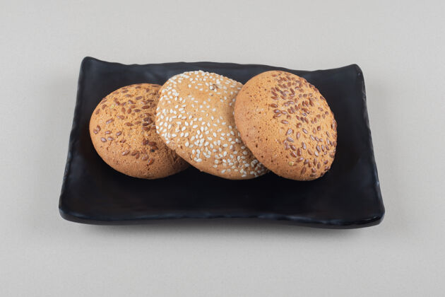 烘焙食品把饼干捆在大理石背景的黑色盘子里涂层甜点饼干